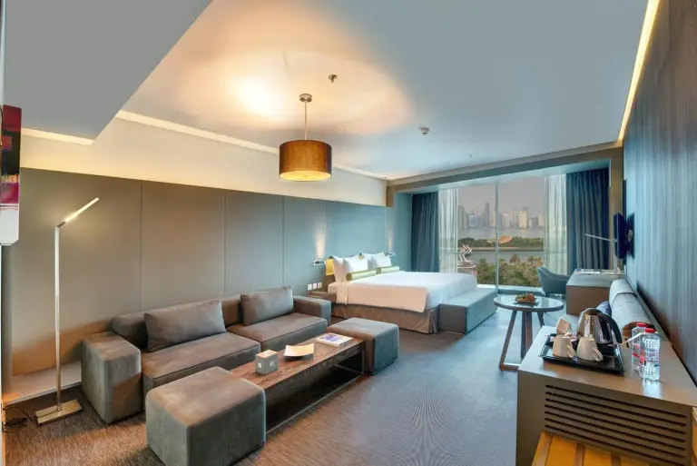 Suite living area at 72 Hotel Sharjah with sofa seating, bed, and window view