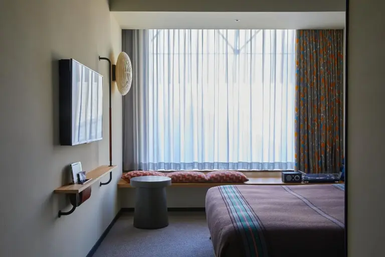 Chambre d’Ace Hotel Kyoto avec banquette de fenêtre et rideaux colorés