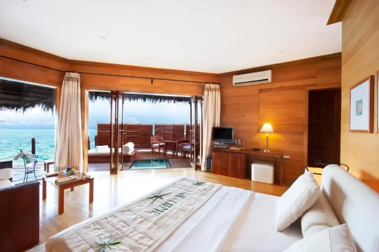 Adaaran Prestige Water Villas - avec Dine around Premium All inclusive - 24 heures – hôtel dans l'atoll de Raa, Maldives – un salon avec un canapé et une télévision dans les Adaaran Prestige Water Villas - avec Dine around Premium All inclusive - 24 heures dans l'atoll de Raa
