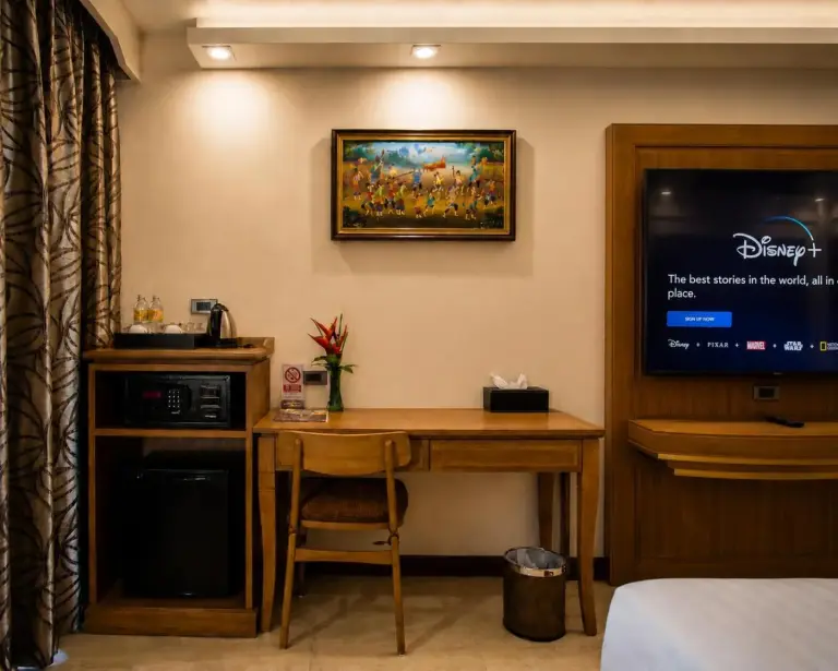Zona de escritorio de la habitación en Aiyara Palace Hotel Pattaya con minibar y televisión