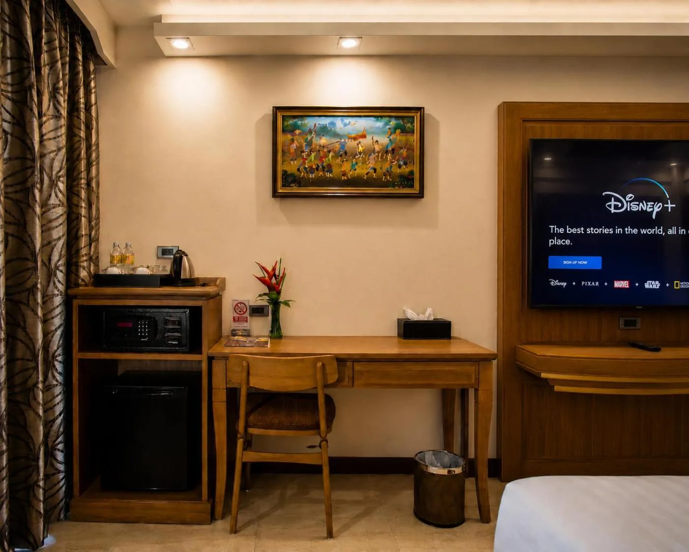 Zona de escritorio de la habitación en Aiyara Palace Hotel Pattaya con minibar y televisión