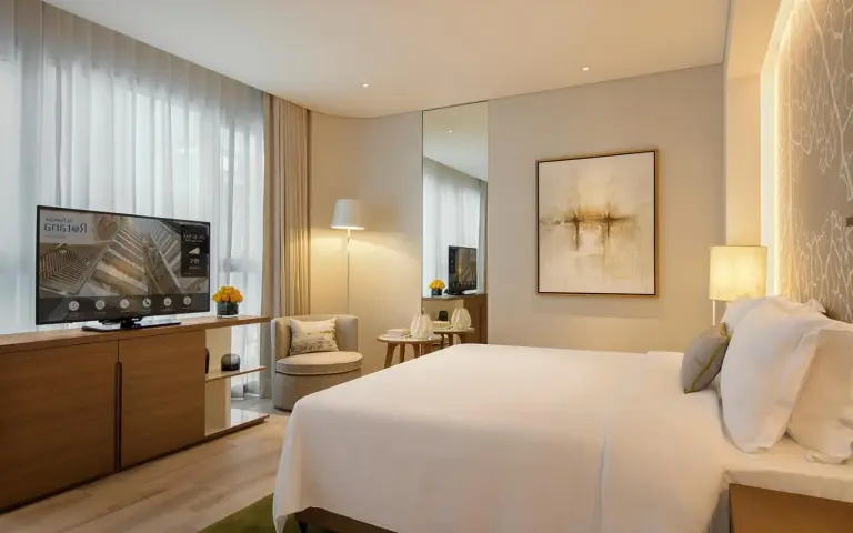 Dormitorio king en Al Bandar Arjaan by Rotana – Dubai Creek en Dubai con TV, sillón y ventana con vistas a la ciudad