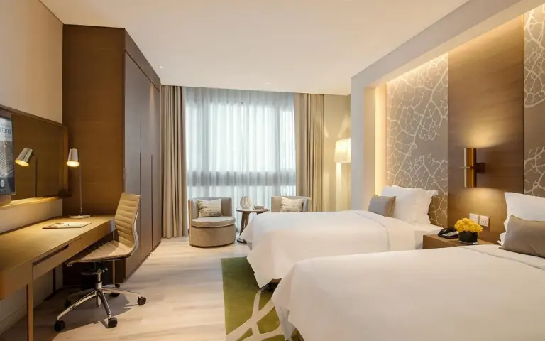 Habitación doble con dos camas en Al Bandar Arjaan by Rotana – Dubai Creek en Dubai con dos camas, escritorio y asiento junto a la ventana
