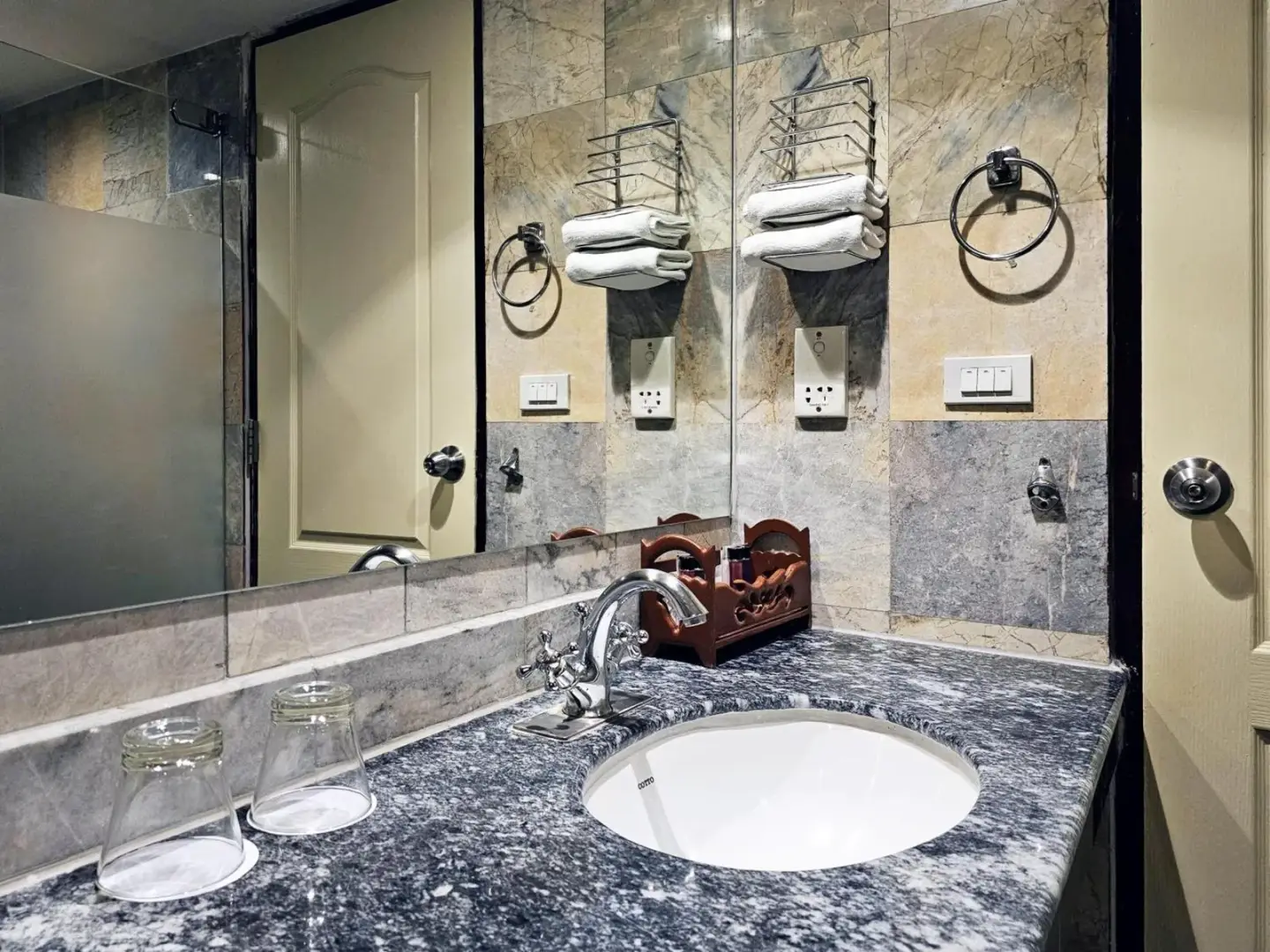 Lavabo de salle de bains du Alexander Hotel Bangkok avec meuble-vasque en marbre, miroir et porte-serviettes