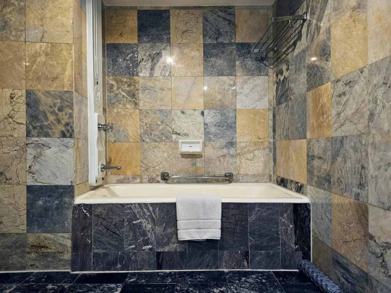 Espace baignoire du Alexander Hotel Bangkok avec murs en carrelage de pierre et porte-serviettes