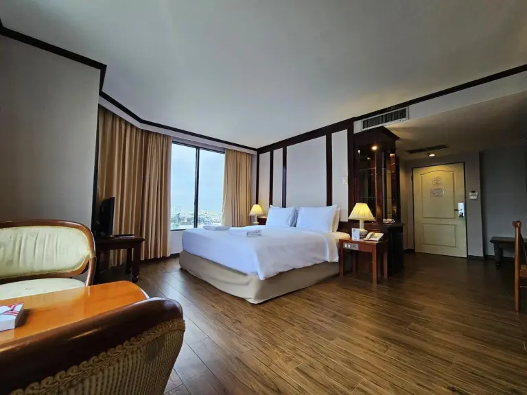 Chambre du Alexander Hotel Bangkok avec lit king size, parquet et fenêtre avec vue sur la ville