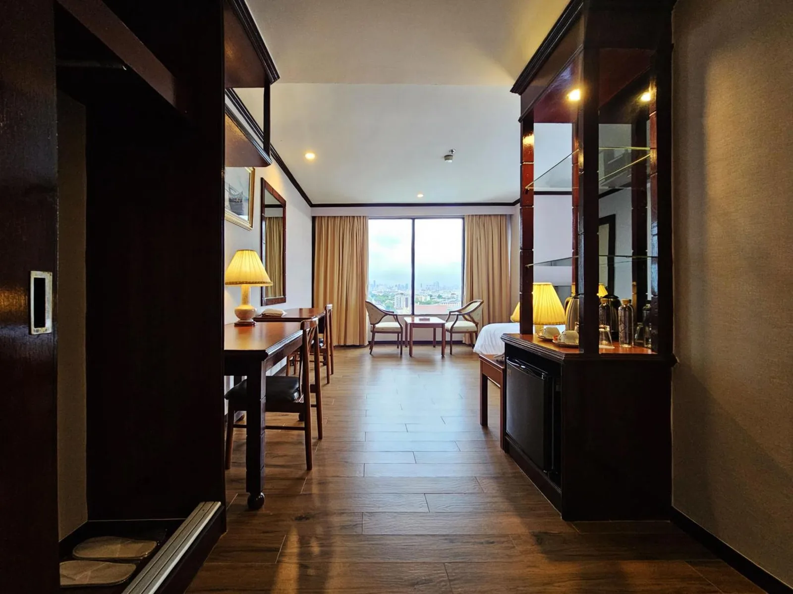 Intérieur de chambre du Alexander Hotel Bangkok avec vue sur le long couloir, bureau et coin fenêtre