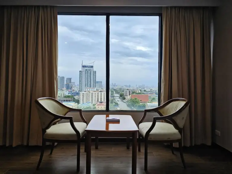 Coin salon du Alexander Hotel Bangkok près d’une grande fenêtre avec vue sur la skyline
