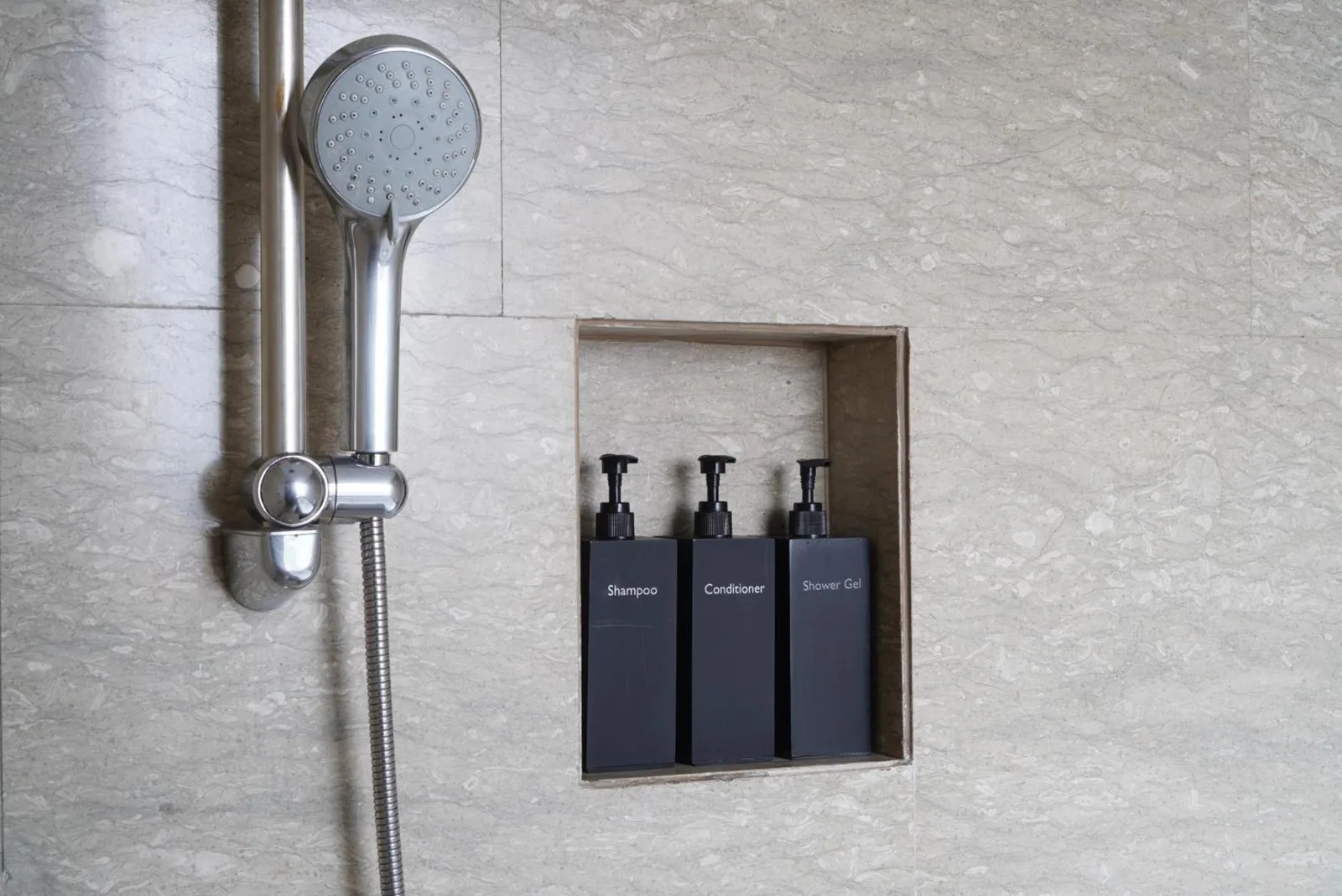Bathroom shower detail at Alila Solo Surakarta with built-in amenity bottles and rainfall shower head