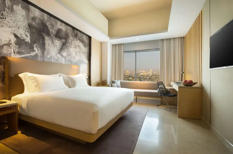 Bright guest room at Alila Solo hotel in Surakarta with king bed, city view, and modern seating area