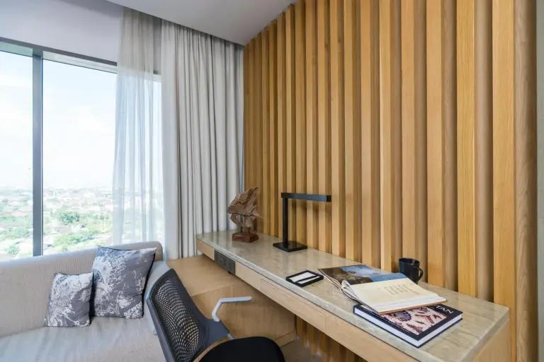 Modern workspace and lounge corner inside Alila Solo hotel room in Surakarta with wooden slat wall
