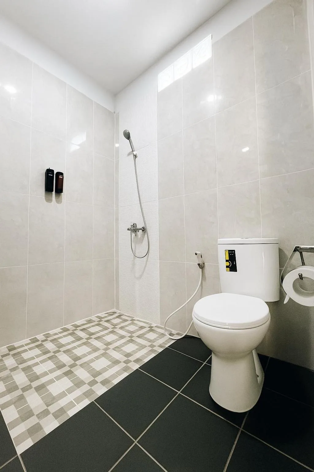 Modern bathroom at Amal Zone Villa in Pontianak with shower, toilet, and tiled wet area.