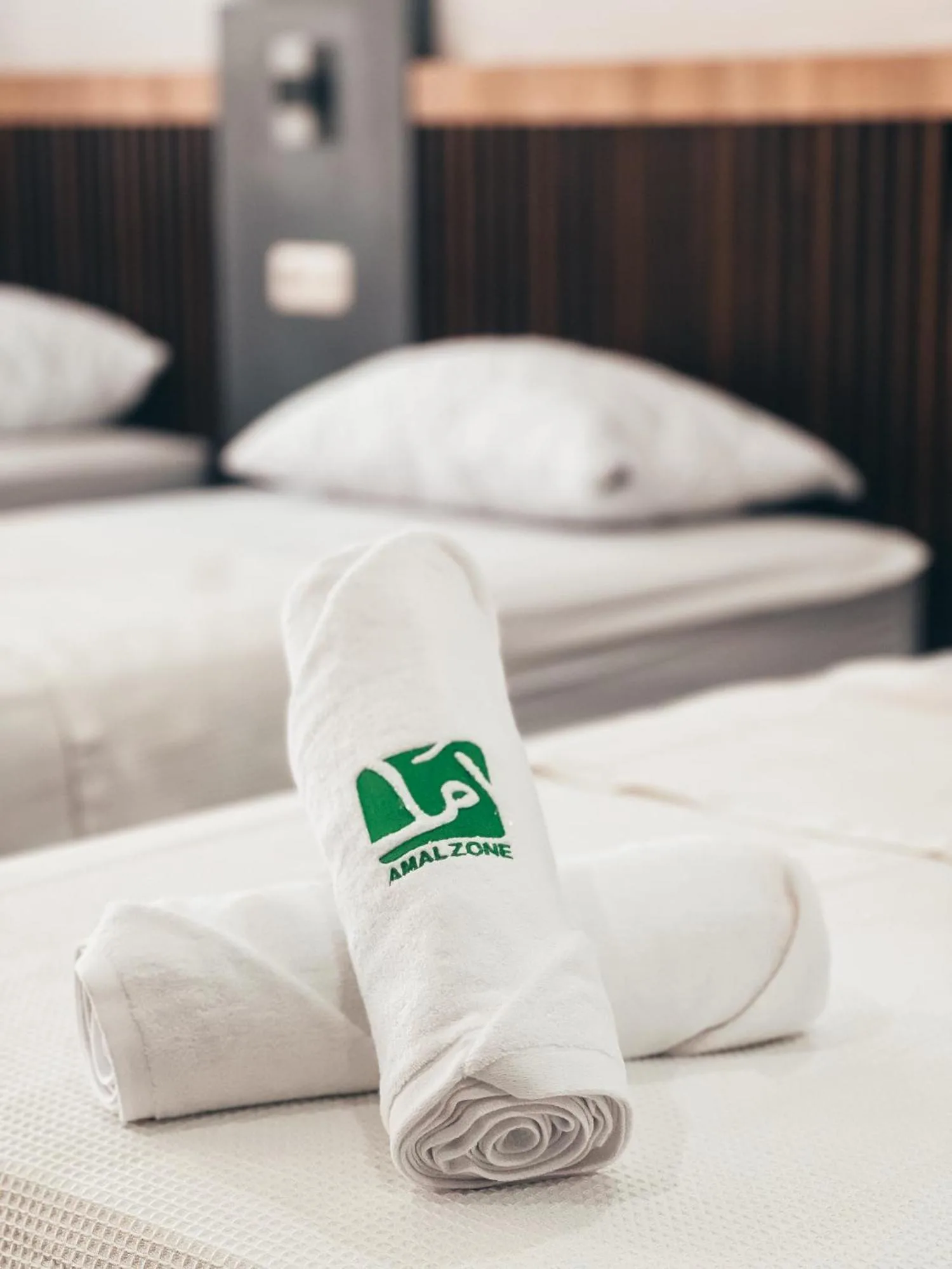 Branded bath towels in a guest room at Amal Zone Villa Pontianak with beds blurred in the background.
