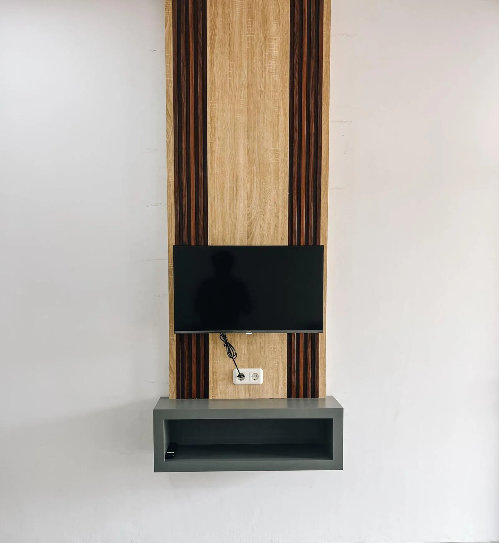 Wall-mounted television and storage shelf inside Amal Zone Villa Pontianak guest room.