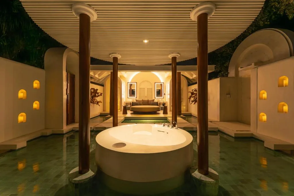 Evening view of the outdoor jacuzzi at Anantara Kihavah Maldives Villas with ambient lighting.