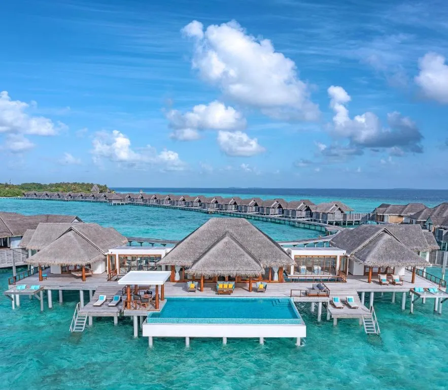 Aerial view of water villas at sunset at Anantara Kihavah Maldives Villas.