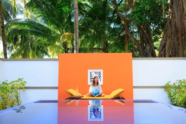 Angsana Velavaru - part of Banyan Group avec transferts aller-retour en hydravion gratuits – hôtel de l’atoll de Dhaalu, Maldives – une femme assise sur une planche de surf sur une table à Angsana Velavaru - part of Banyan Group avec transferts aller-retour en hydravion gratuits dans l’atoll de Dhaalu