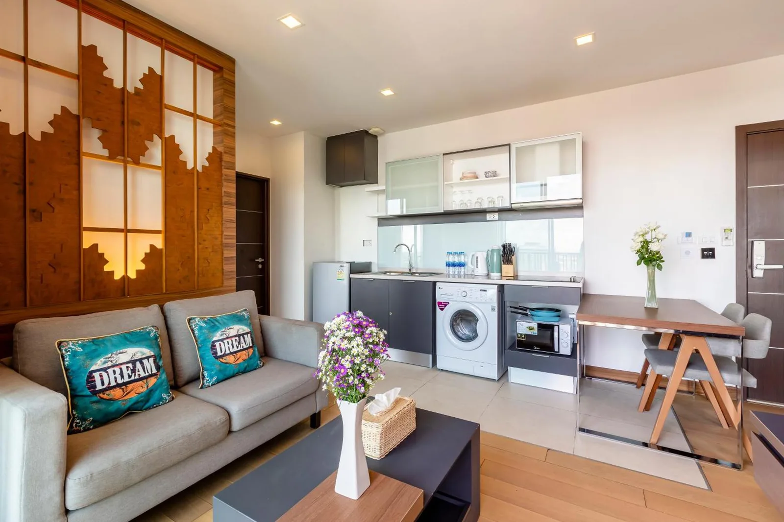 Sala de estar y cocina de planta abierta en Anta Residence Self-service apartment en Chiang Mai con sofá y zona de lavandería