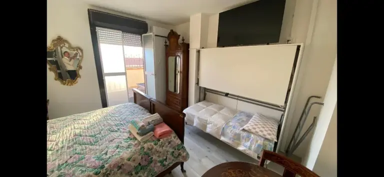 Dormitorio doble en Appartamenti con Terrazzo Solare en Perugia con colcha floral, armario, TV y acceso al balcón