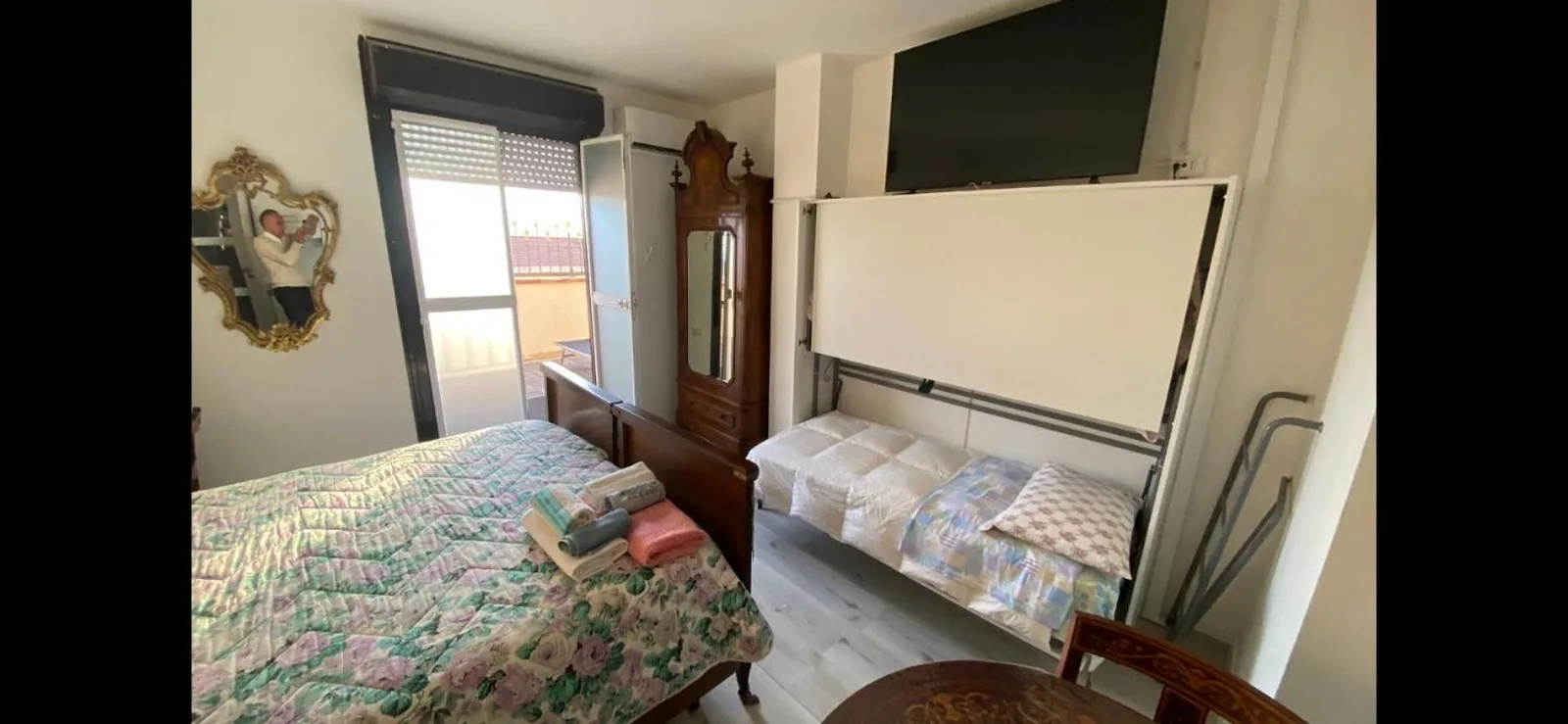 Dormitorio doble en Appartamenti con Terrazzo Solare en Perugia con colcha floral, armario, TV y acceso al balcón