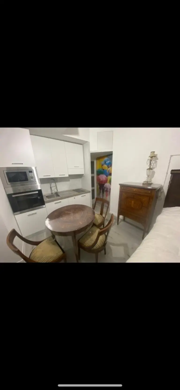 Pequeña zona de cocina y mesa de comedor en Appartamenti con Terrazzo Solare, Perugia, con armarios blancos y muebles de madera