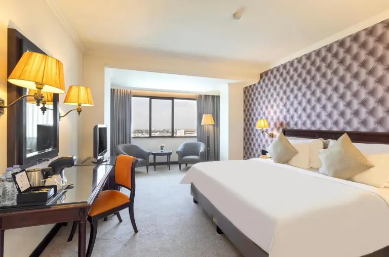Hotel room at ARTOTEL Suites Aquila Bandung with king bed, seating area, and a panoramic city view through the window