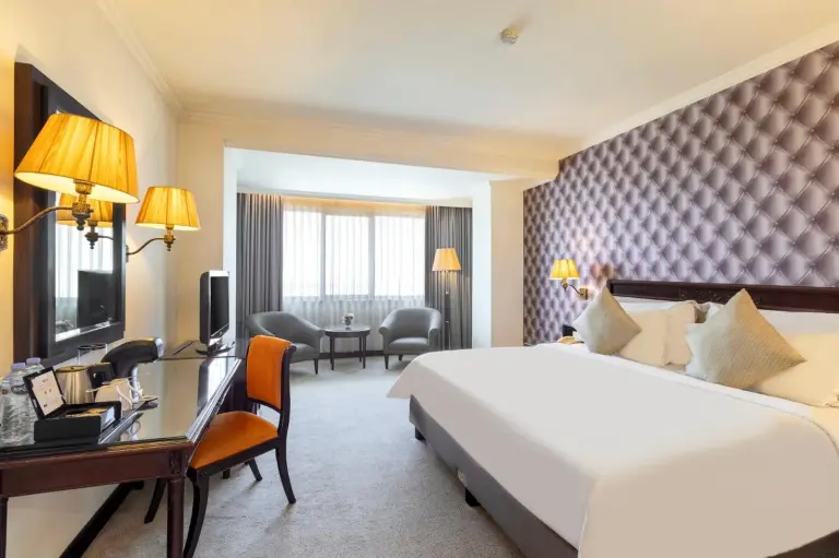 Deluxe guest room at ARTOTEL Suites Aquila Bandung featuring a king bed, work desk, seating area, and city view