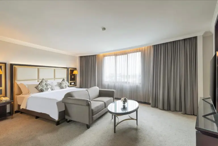 Large suite room at ARTOTEL Suites Aquila Bandung with bed, sofa, TV area, and window seating