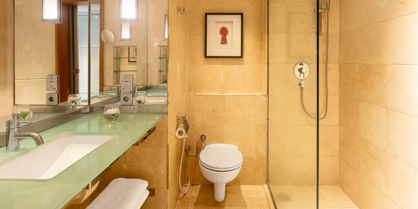 Salle de bains de Aryaduta Menteng à Jakarta avec douche vitrée, lavabo et toilettes dans une finition en pierre.