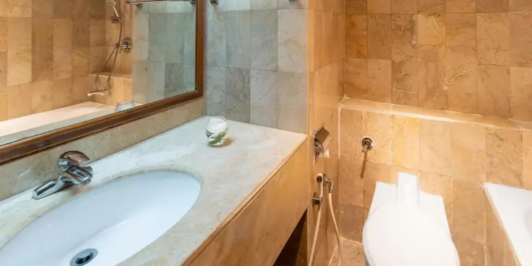 Meuble vasque et lavabo de la salle de bains de Aryaduta Menteng à Jakarta avec miroir et espace baignoire.