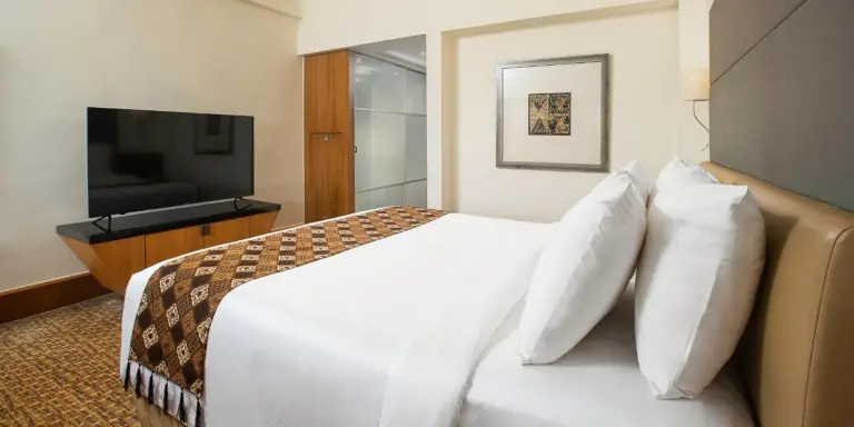 Chambre king de Aryaduta Menteng à Jakarta avec un grand lit, une télévision et un design intérieur moderne.