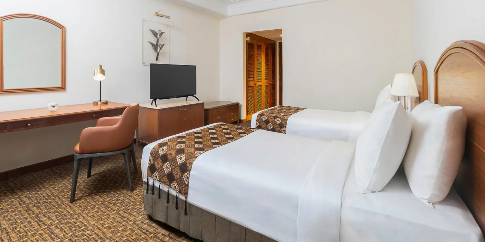 Chambre d’hôtes twin de Aryaduta Menteng à Jakarta avec deux lits simples, un bureau et une télévision.