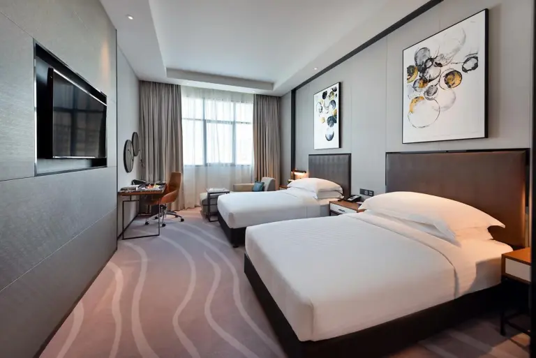 Asiana Grand Hotel Dubai Double Room mit einem King-Bett, zwei Stühlen und einem TV-Schrank