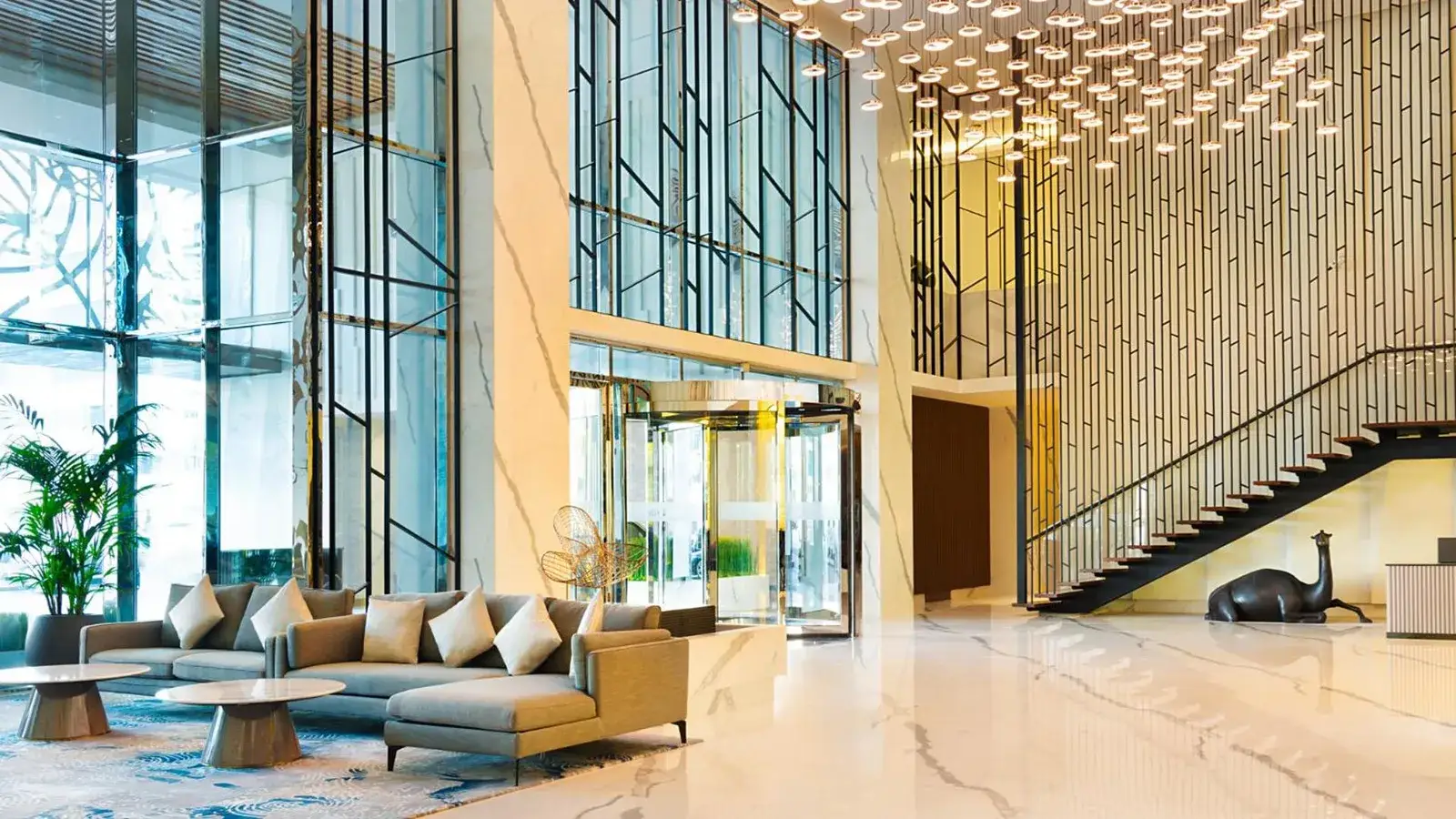 Asiana Grand Hotel Dubai Lobby mit modernen Sitzgelegenheiten, hohen Glaswänden und einer geschwungenen Treppe