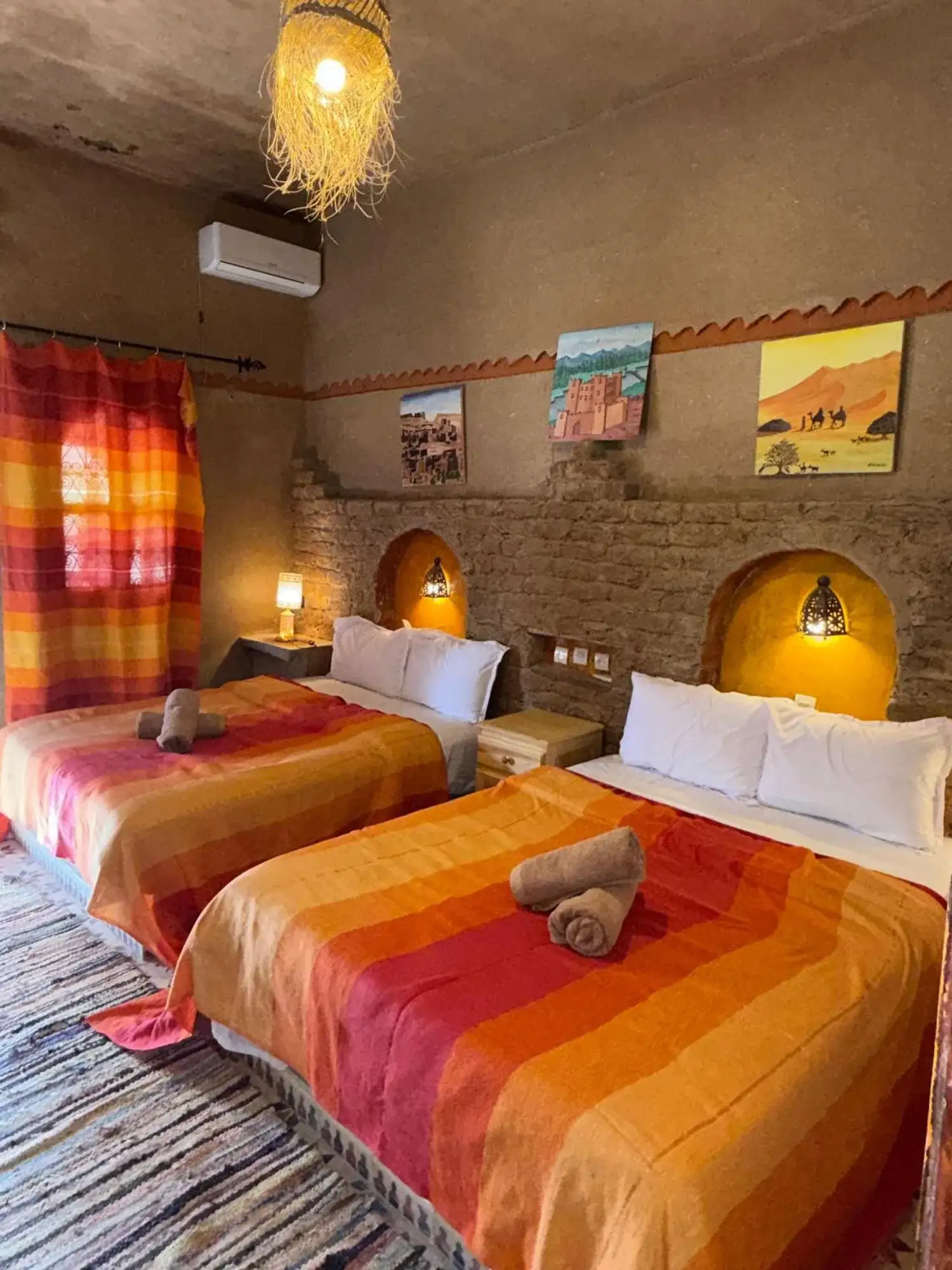 Chambre Twin à Auberge Camping La Libertè à Merzouga avec couvre-lits rayés colorés et décoration traditionnelle du désert