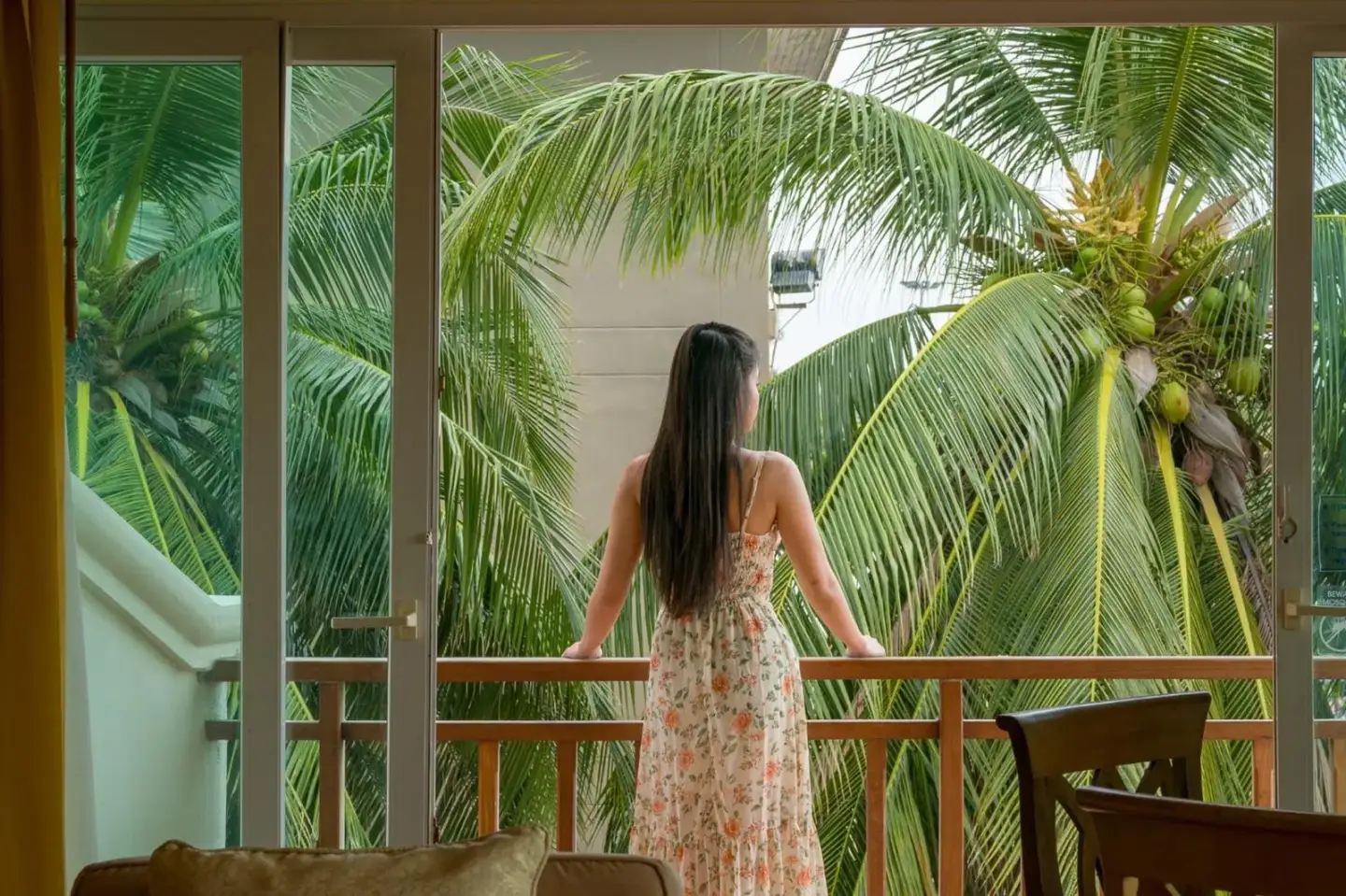 Huésped disfrutando de la vista desde el balcón de Avalon Beach Resort Pattaya con palmeras tropicales al exterior.