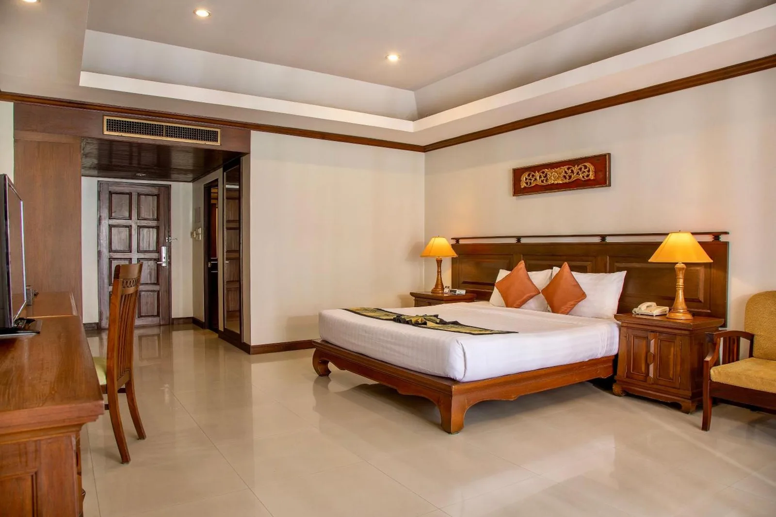 Interior clásico de una habitación de huéspedes en Avalon Beach Resort Pattaya con cama, escritorio y zona de estar.
