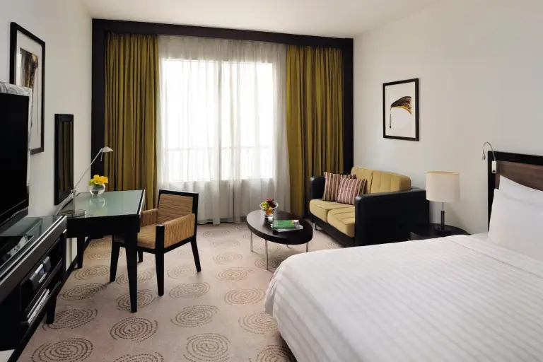 Geräumiges Gästezimmer im Avani Deira Dubai Hotel in Dubai mit Bett, Sitzbereich und Fenster