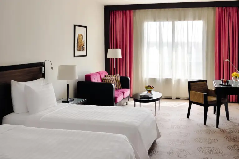 Zweibett-Gästezimmer im Avani Deira Dubai Hotel in Dubai mit zwei Betten und Sitzbereich