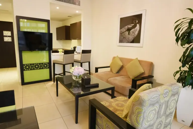 Espace de vie de type appartement au Bahi Ajman Palace Hotel à Ajman avec canapé, télévision et accès à la cuisine