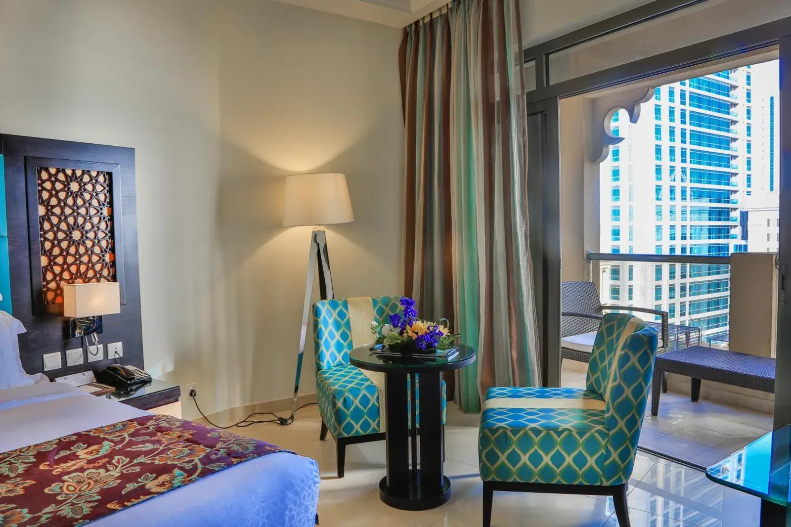 Chambre avec balcon au Bahi Ajman Palace Hotel à Ajman avec coin salon et vue sur les tours voisines