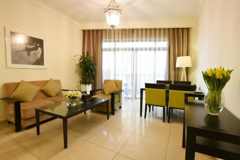 Salon de suite au Bahi Ajman Palace Hotel à Ajman avec canapé, table basse et coin repas