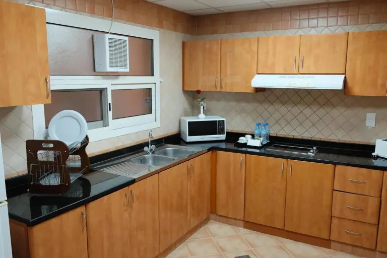 Fully equipped kitchen at Baity Hotel Apartments in Dubai with cabinets, sink, stove, and microwave.