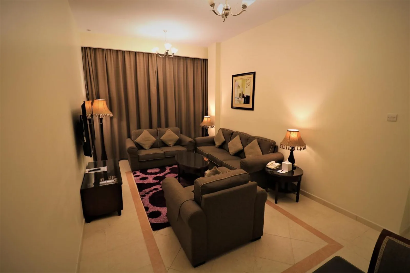 Living room inside Baity Hotel Apartments in Dubai with sofas, lamps, and a television.