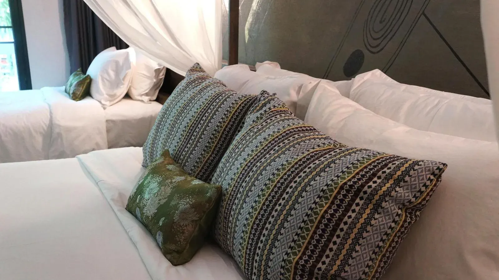 Bamboori Boutique Resort Chiang Mai bed with patterned pillows and white canopy drapes