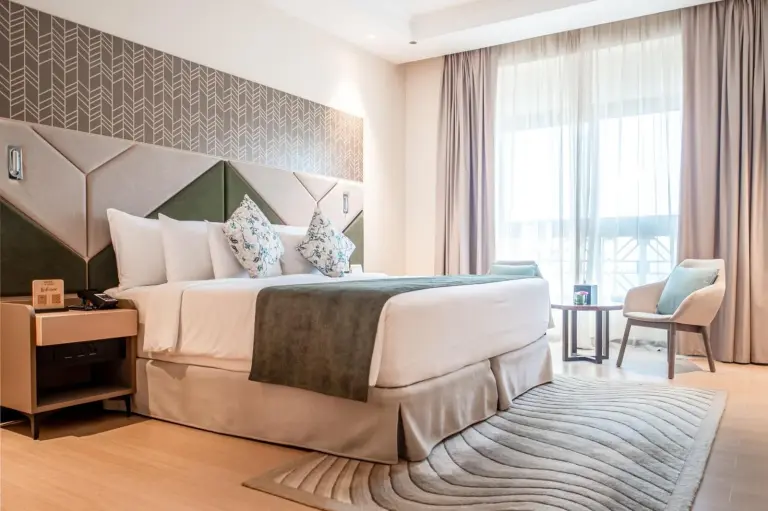 Stilvolle Suite im Barcelo Al Jaddaf, Dubai mit King-Bett, Sessel und natürlichem Licht