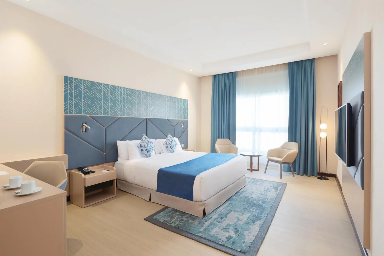 Twin-Gästezimmer im Barcelo Al Jaddaf, Dubai mit großem Fenster, blauen Vorhängen und Stadt-Skyline