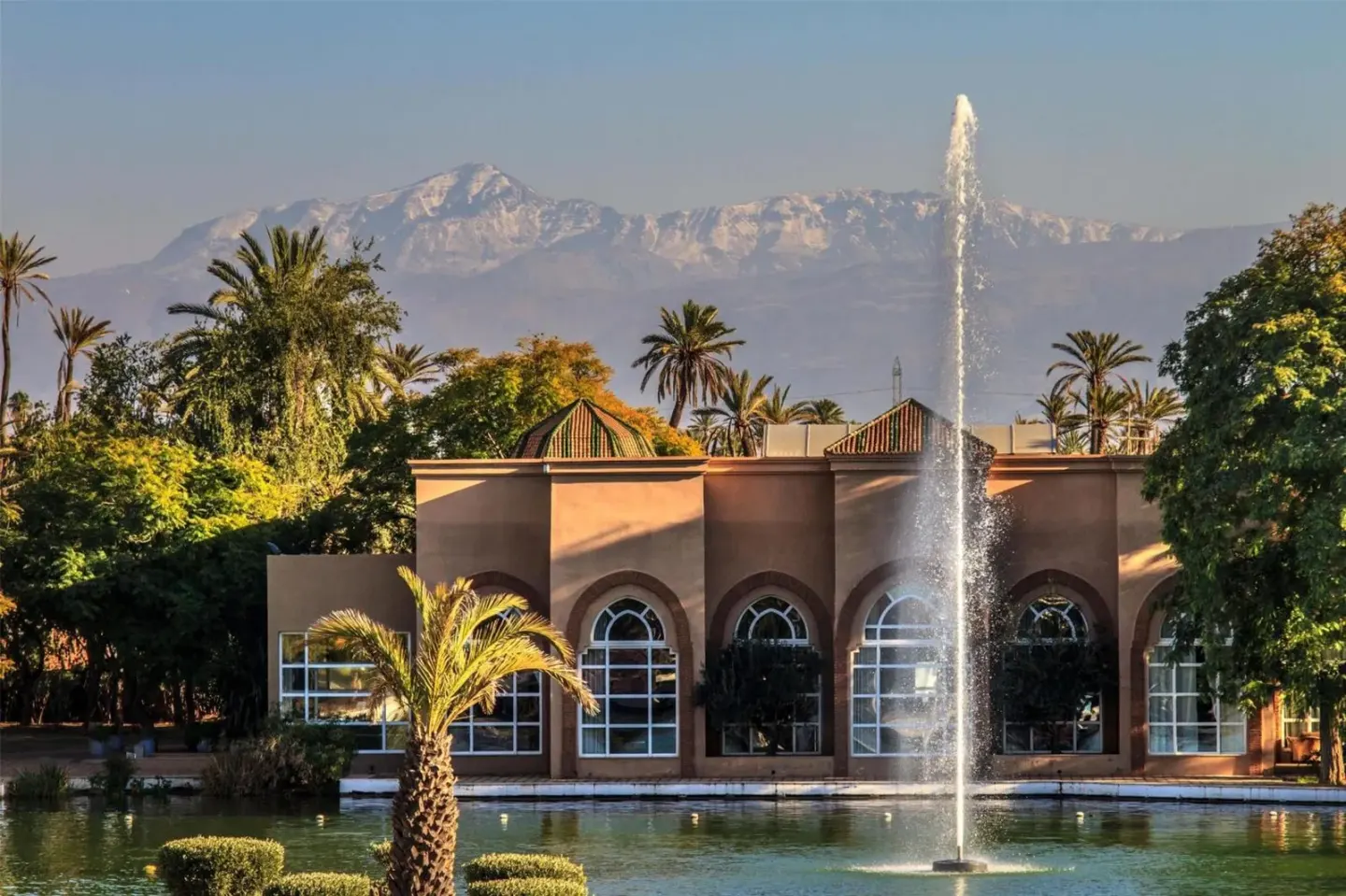 Außenansicht des Barceló Palmeraie Oasis Resort in Marrakesch mit einem Brunnen und Bergen