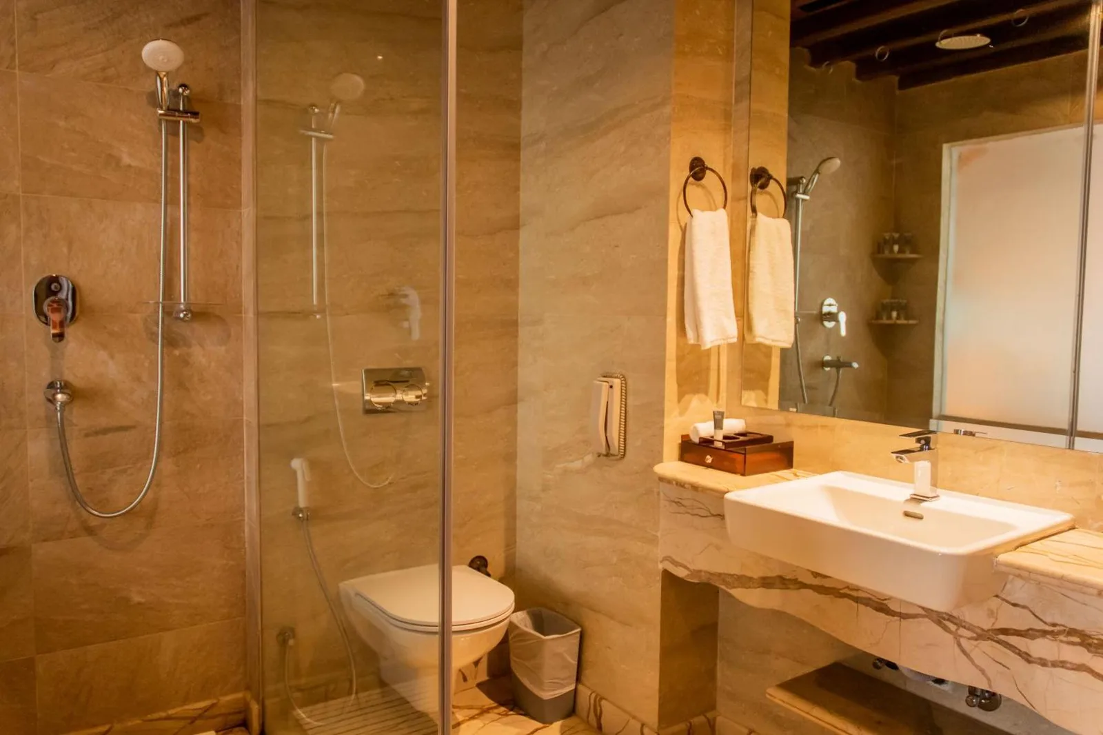 Elegante tocador y zona de ducha en Basera Boutique Hotel - La escapada oculta de Kathmandu, con lavabo de mármol y mampara de cristal.