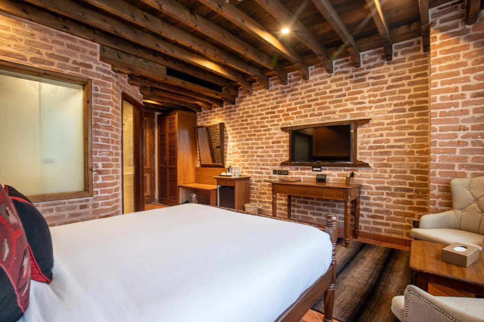 Un dormitorio con paredes de ladrillo en Basera Boutique Hotel - La escapada oculta de Kathmandu, con TV montada en la pared y mobiliario de madera.